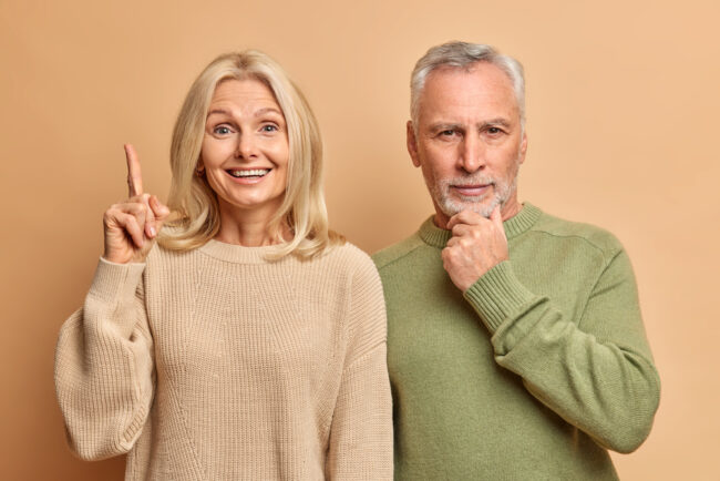 Positive,Blonde,Woman,Points,Above,With,Glad,Expression,Wears,Casual