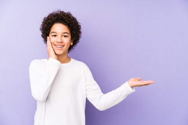 african-american-little-boy-isolated-holds-copy-space-palm-keep-hand-cheek-amazed-delighted_1187-120175