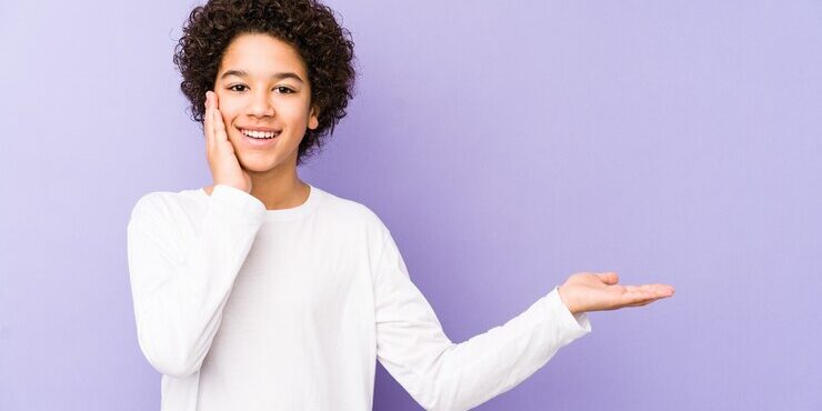 african-american-little-boy-isolated-holds-copy-space-palm-keep-hand-cheek-amazed-delighted_1187-120175