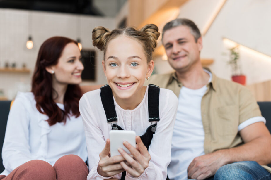 Mature,Parents,And,Teen,Girl,With,Smartphone,In,Cafe